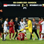 Insiden tak terpuji mewarnai pertandingan sepak bola putra SEA Games 2025 antara Timnas Indonesia U-22 dan Timnas Myanmar U-22, Jumat (13/12/2025). Laga yang berlangsung di 700th Anniversary Stadium, Chiang Mai, Thailand, itu berjalan dalam tensi tinggi. Skuad Merah Putih tampil ngotot karena membutuhkan kemenangan besar demi menjaga peluang lolos ke semifinal. Peluit Panjang Picu Keributan Intensitas pertandingan meningkat tajam menjelang laga berakhir. Puncaknya terjadi saat wasit meniup peluit panjang setelah bola keluar lapangan, menandai berakhirnya pertandingan. Keputusan tersebut memicu protes keras dari sejumlah pemain Indonesia. Ivar Jenner dan Zanadin Fariz diganjar kartu kuning akibat aksi protes. Situasi kian memanas ketika Zanadin harus menerima kartu merah, lantaran sebelumnya sudah mengoleksi satu kartu kuning. Kiper Myanmar Tendang Dion Markx Setelah kartu merah dikeluarkan, beberapa pemain Timnas Indonesia U-22 kembali mendekati wasit untuk mempertanyakan keputusannya. Protes juga datang dari pemain pengganti yang mengenakan rompi biru muda dan sempat merangsek masuk ke lapangan dari area bangku cadangan. Dalam situasi tersebut, bek Timnas Indonesia U-22 Kadek Arel terlihat berlari menuju tengah lapangan. Ia berupaya menarik Dion Markx, yang sedang terlibat adu mulut dengan pemain Myanmar. Meski sempat dilerai, Dion kembali terlibat friksi dengan penjaga gawang lawan. Aksi saling dorong pun tak terhindarkan hingga akhirnya kiper cadangan Myanmar U-22 melayangkan tendangan ke arah Dion Markx. Aksi tersebut menjadi pemicu utama kericuhan besar di tengah lapangan. Sejumlah pemain dari kedua tim langsung berusaha melerai agar situasi tidak semakin meluas. Indra Sjafri dan Sumardji Turun Tangan Para pemain Indonesia dan Myanmar tampak berupaya menenangkan keadaan. Dion Markx ditarik dan diredam oleh rekan-rekannya, sementara kiper Myanmar U-22 Khant Min Thant yang terlihat emosional juga segera dilerai oleh sesama pemain. Tak hanya pemain, jajaran ofisial dan tim pelatih dari kedua kubu turut turun ke lapangan. Pelatih Timnas Indonesia U-22 Indra Sjafri, bersama para asistennya seperti Bima Sakti dan Zulkifli Syukur, serta manajer tim Sumardji, terlihat aktif menenangkan situasi. Situasi Berhasil Dikendalikan Beruntung, kericuhan dan adu fisik tersebut tidak berkembang lebih jauh. Ofisial kedua tim meminta para pemain untuk segera meninggalkan lapangan dan kembali ke bangku cadangan masing-masing. Pertandingan pun akhirnya benar-benar berakhir tanpa insiden lanjutan, meski meninggalkan catatan kelam akibat kericuhan usai peluit panjang.